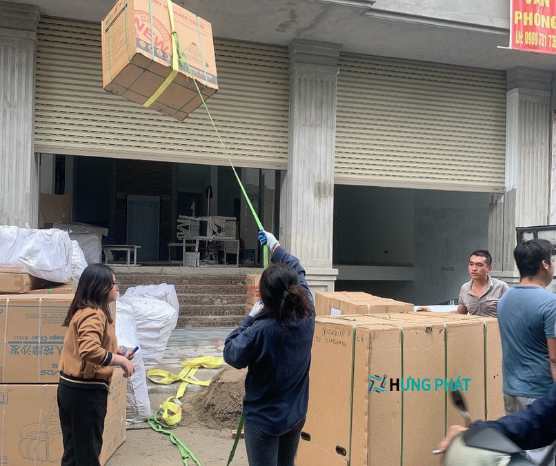 4 người đang vận chuyển thùng hàng từ trên cao xuống bằng dây cột